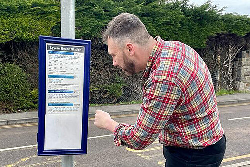 Cllr Simon Johnson reading bus timetable