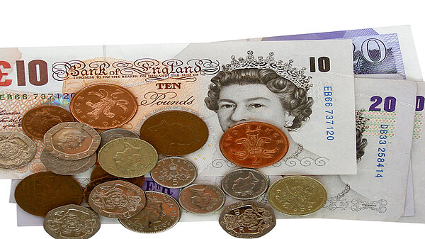 A pile of pound coins on top of notes.