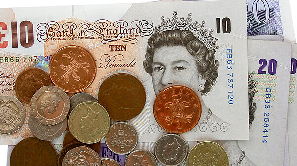 A pile of pound coins on top of notes.